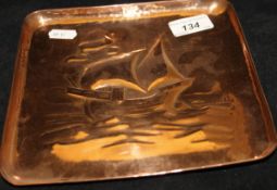 A Newlyn School Arts and Crafts square copper tray with embossed decoration of a galleon at sea,