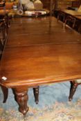 A mahogany rounded rectangular dining table on turned and reeded balluster supports to castors (3
