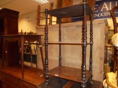 A mahogany three tier whatnot with turned supports, raised on brass caps and brown china castors,