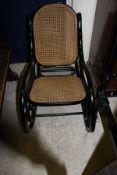 An ebonised framed bentwood rocking chair with cane seat and back by Thonet,