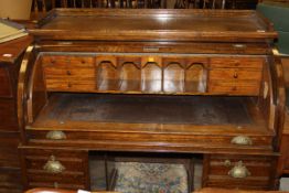 An early 20th Century oak roll top pedestal desk