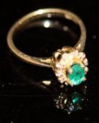 A 14 carat gold ring set with emerald surrounded by ten chip diamonds