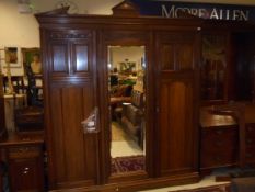 An Edwardian mahogany bedroom suite to include three door wardrobe with architectural pediment