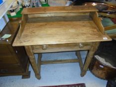 A Victorian pine desk with three quarter galleried top above a single door raised on ringed and