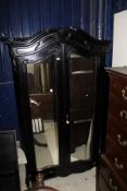 A black painted armoire with two mirrored doors above a single drawer