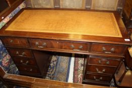 A 20th Century mahogany pedestal desk of nine drawers with an orange leatherette inset top