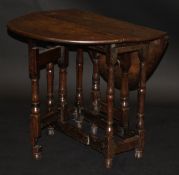 An 18th Century oak oval gate-leg side table with turned supports on a structured base and turned