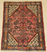 A Persian rug, the central panel set with all over floral design, on a red and cream ground,