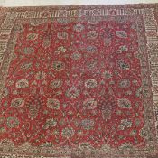 A Persian carpet, the central panel set with all-over scrolling foliate decoration on a red ground,