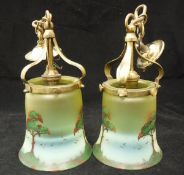 A pair of Arts & Crafts style hanging lamps, the brass mounts supporting coloured glass shades,