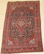 A Persian carpet, the central panel set with a floral decorated medallion on a blue ground,