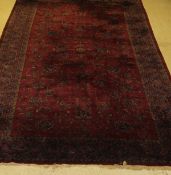 A Persian rug, the central panel with repeating floral sprays on a puce ground,