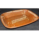 A 19th Century rectangular slip ware dish decorated with cream separate line decoration on a brown