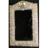A late Victorian silver framed mirror with all-over C scroll and foliate decoration with blank