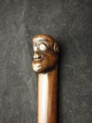 An Eastern hardwood walking cane, the handle formed as monkey head with ivory eyeballs,