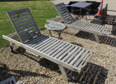 A pair of modern teak Lindsey plantation sun loungers with integral tables and cushions together