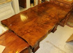 A 1930's walnut dining table, the shaped top supported by two pillars,