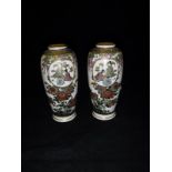 A pair of Japanese Meiji Period Satsuma vases decorated with panels of figures in an interior