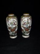 A pair of Japanese Meiji Period Satsuma vases decorated with panels of figures in an interior