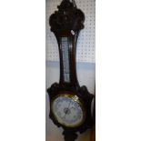 A late Victorian aneroid barometer thermometer in a carved oak case