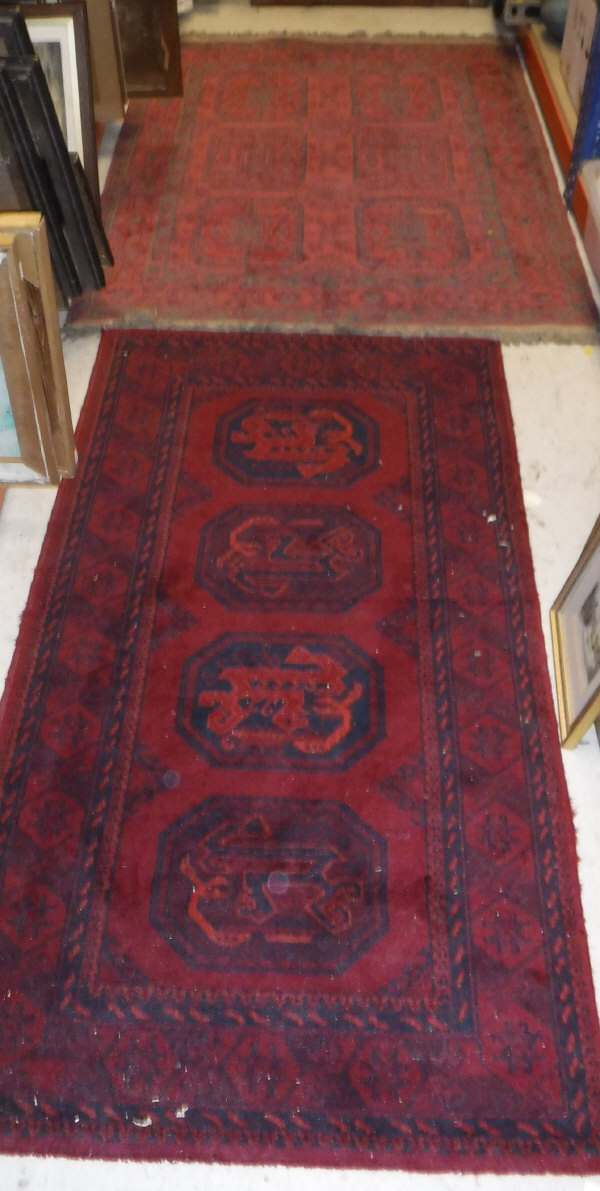 A Turkoman rug, the central panel set with four repeating medallions on a blood red ground,