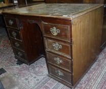A mahogany desk with green tooled leather inset top over various drawers and a cupboard door to the