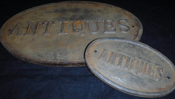 A reproduction painted cast iron "Antiques" sign and another similar smaller*