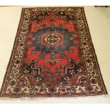 A Persian rug, the central panel set with a stylised star burst medallion with blue and red ground,