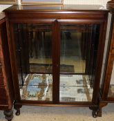 An early 20th Century mahogany two door display cabinet enclosing glass shelves on cabriole legs,