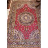 A Persian rug, the central panel set with floral decorated circular medallion on a pink ground,