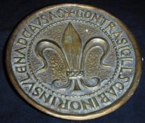 A bronze plaque by Max Le Verrier decorated with fleur de lys within a script border,