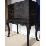 A Chinese lacquered and painted cabinet on stand, the top with engraved brass embellishments,