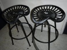 A pair of modern iron tractor seat stools with adjustable seats *