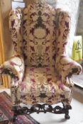 A modern upholstered wing back scroll arm chair in the 18th Century Flemish taste raised on moulded