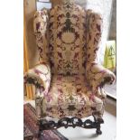 A modern upholstered wing back scroll arm chair in the 18th Century Flemish taste raised on moulded
