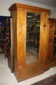 A late 19th Century walnut single door wardrobe with ogee moulded pediment and single mirrored door,
