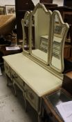 A modern cream painted dressing table with triple mirror above a plain top over a single drawer