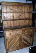 A pine dresser with two tier boarded plate rack over two drawers and two cupboard doors