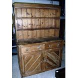 A pine dresser with two tier boarded plate rack over two drawers and two cupboard doors