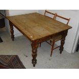 A rectangular plank top rustic pine kitchen table on turned supports
