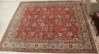 A Persian carpet, the central panel set with all-over scrolling foliate decoration on a red ground,