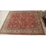 A Persian carpet, the central panel set with all-over scrolling foliate decoration on a red ground,