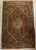 A Persian rug, the central panel set with lozenge shaped medallions on a red,