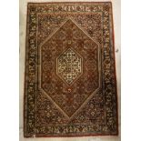 A Persian rug, the central panel set with lozenge shaped medallions on a red,