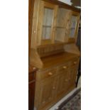 A 20th Century pine kitchen dresser with open shelves flanked by glazed cupboard doors on a base of