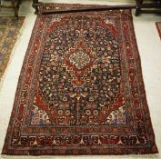 A Persian carpet, the central panel set with a floral decorated medallion on a blue ground,