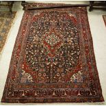 A Persian carpet, the central panel set with a floral decorated medallion on a blue ground,