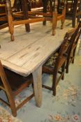 A pine plank top rectangular kitchen table with cleated end supports on square section legs,