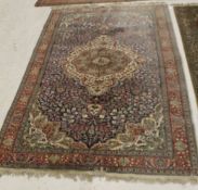 An Oriental carpet, the central panel set with a floral decorated medallion on a blue ground,