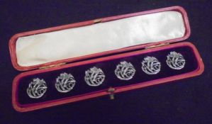 A cased set of six Edwardian silver pierced buttons with floral decoration in the Art Nouveau taste